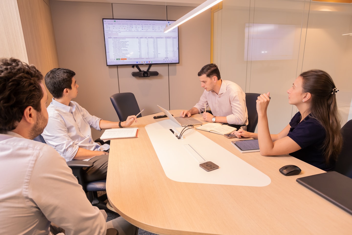 Business professionals collaborating around a screen in a conference room.